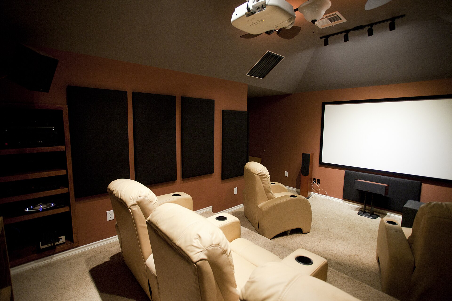 Acoustic absorption panels mounted on the side walls of a home cinema, either side of tiered seating